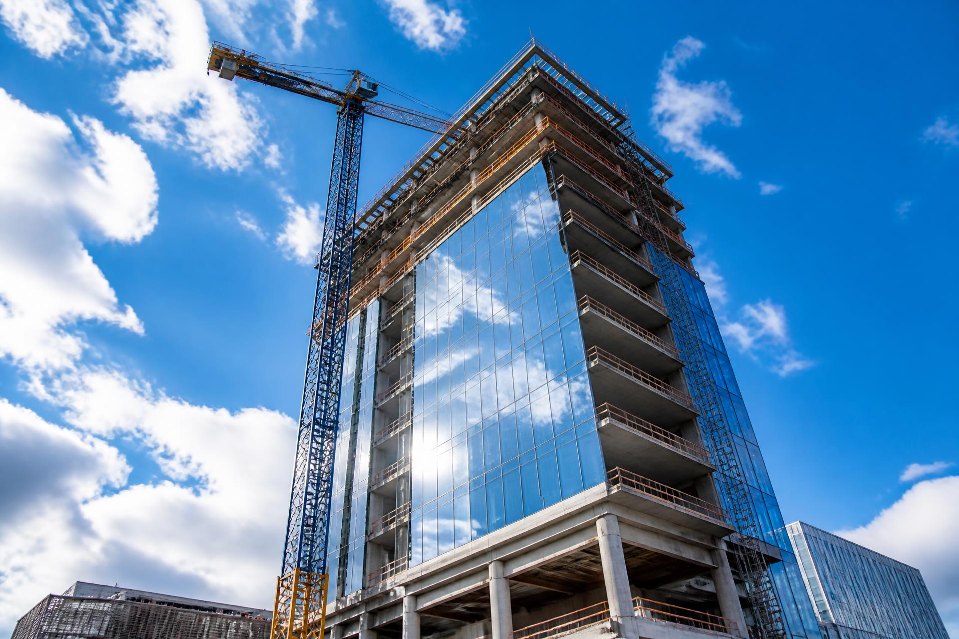High-rise building under construction with a tower crane at golden hour